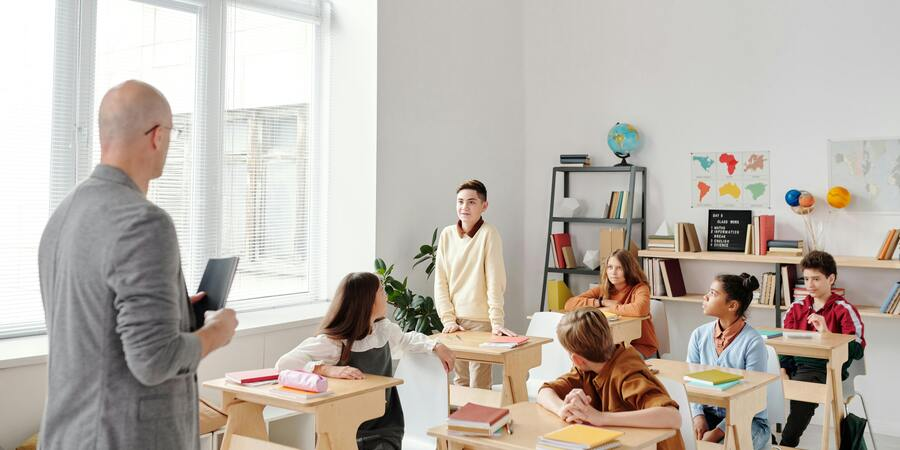 A boy introducing his self in front of teacher and classmates.